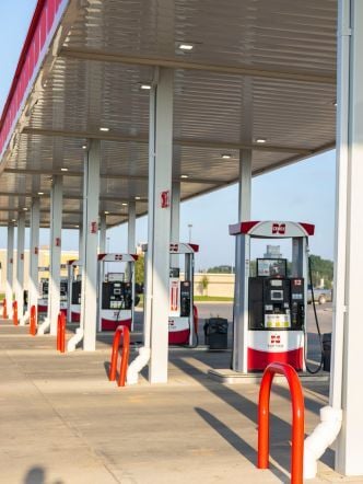 Fuel station canopy covering multiple pump islands, with red bollards.