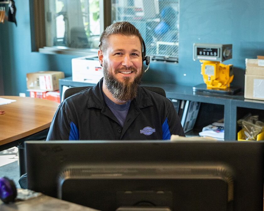Customer service representative wearing a headset, smiling at the front desk.