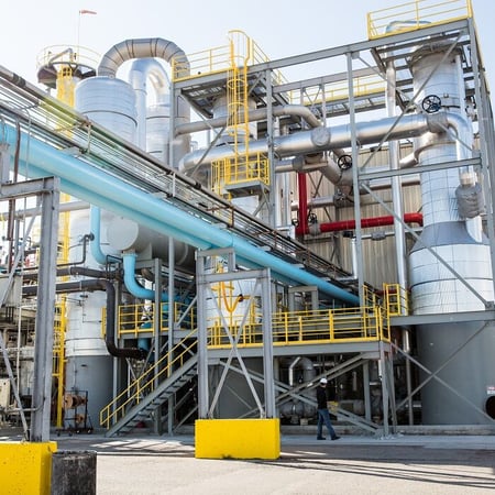 Ethanol plant with large piping, tanks, and elevated platforms with yellow safety railings.