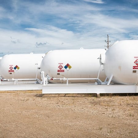 Row of white horizontal propane storage skid tanks.