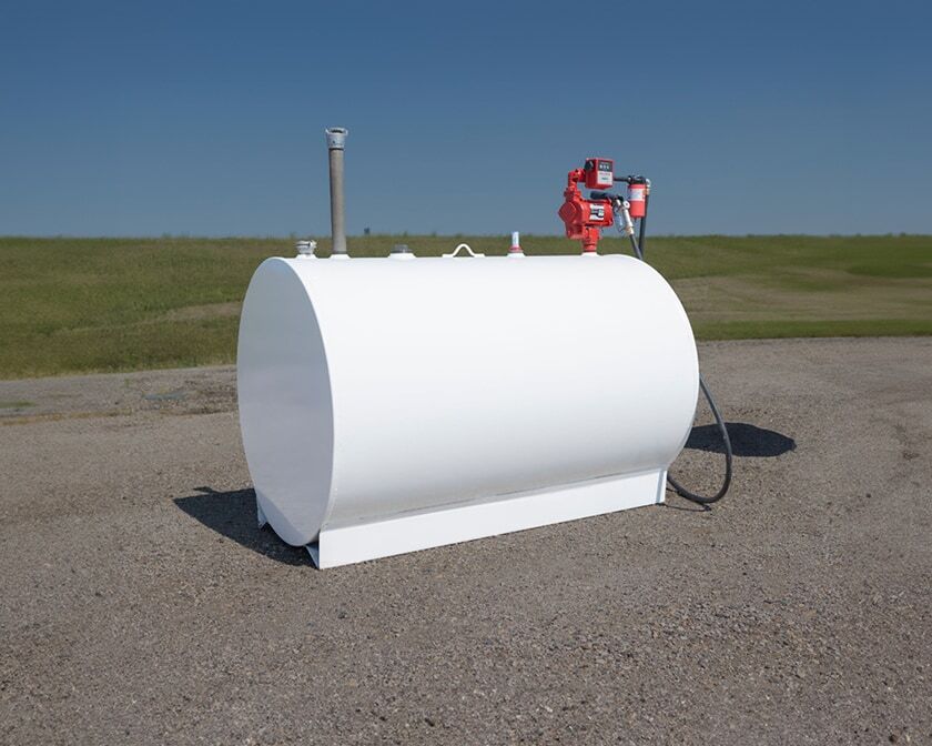 White horizontal farm skid tank with pump assembly and hose, set on a gravel pad under a clear sky.