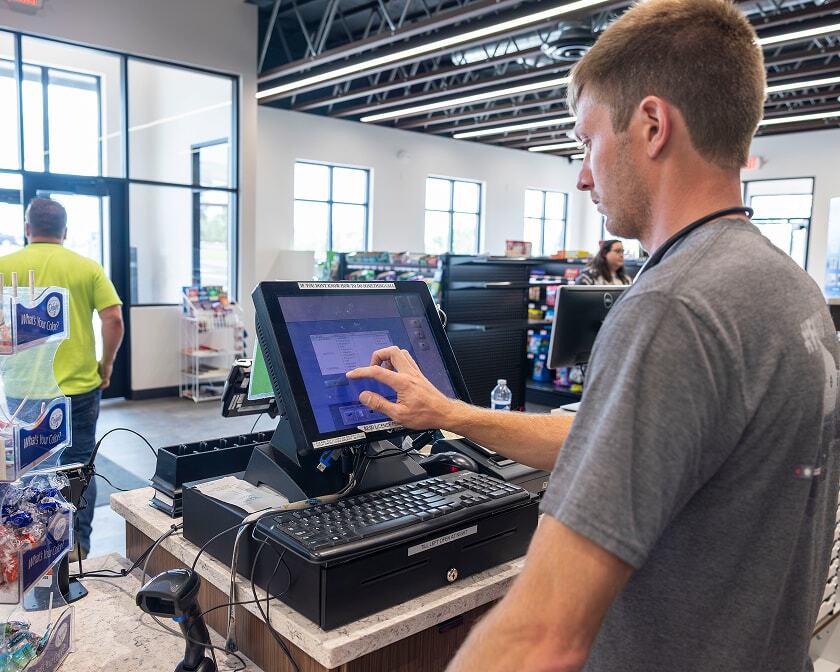 Westmor technician setting up a touchscreen POS system at a convenience store checkout counter.